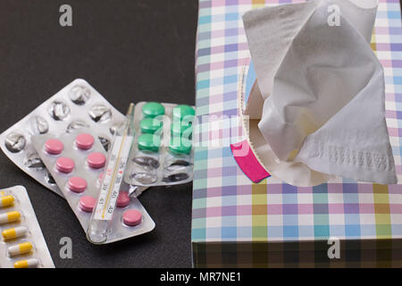 Pillen, Thermometer, Papier Serviette und zerknitterte Serviette auf. Ansicht von oben, Medizin Konzept Foto. Schwarzer Hintergrund Stockfoto