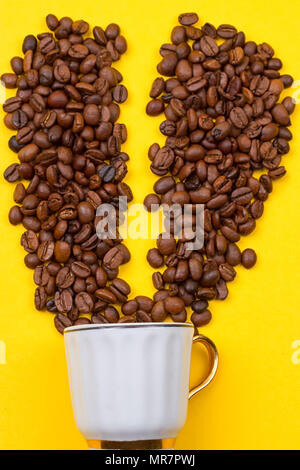 Eine Tasse Kaffee und die Herzen der Bohnen auf gelbem Hintergrund Stockfoto