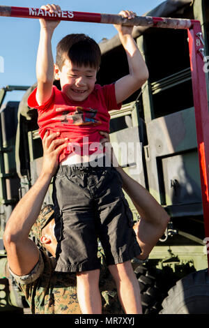 Körperliches Fitnesstraining ist eine Grundvoraussetzung für Personal des United States Marine Corps. Das Archivbild dokumentiert einen Marine, der einem Kind bei einer Pull-up-Übung während einer Feierlichkeiten zum Tag der öffentlichen Streitkräfte in Torrance, Kalifornien, am 20. Mai 2017 hilft. Stockfoto