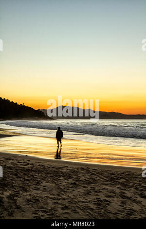 Silhouette der Person zu Fuß auf lagoinha Strand bei Sonnenuntergang. Florianopolis, Santa Catarina, Brasilien. Stockfoto