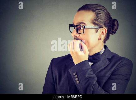 In dem Bestreben, junge Mann seine Fingernägel beißen auf die Seite schauen Beschäftigt Stockfoto