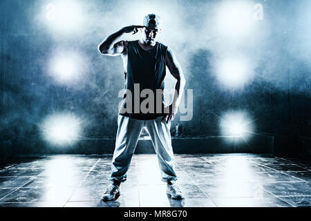 Junger Mann Breakdancer im Club mit Licht und Rauch. Tattoo am Körper. Blau getönten Farben. Stockfoto