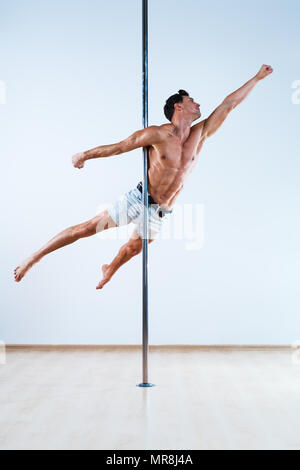 Junge Pole Dancing Mann auf weißen und blauen Wand Hintergrund Stockfoto