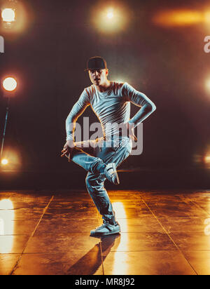 Junger Mann pause Tanzen im Club mit Licht und Rauch. Warme Farben. Stockfoto