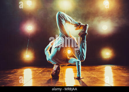 Junger Mann pause Tanzen im Club mit Licht und Rauch. Warme Farben. Stockfoto