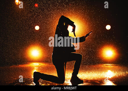 Junger Mann Breakdancer dramatische Silhouette in Club mit Licht und Wasser Stockfoto