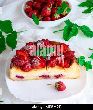 Die Hälfte Käsekuchen von Hüttenkäse und frische Erdbeeren auf einem weißen Keramik Teller gemacht, Ansicht von oben, weißer Hintergrund Stockfoto