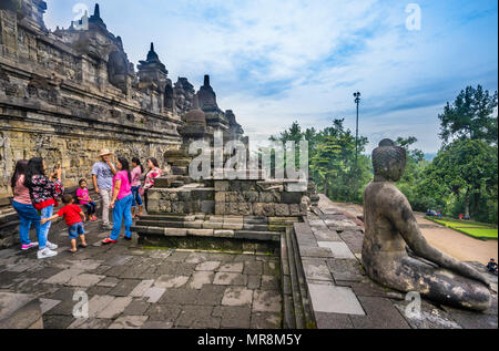 Besucher bewundern die Reliefs, erzählt eine umfassende buddhistische Erzählung am Borobudur buddhistischen Tempel, Zentraljava, Indonesien Stockfoto