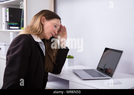 Seitenansicht eines reifen Geschäftsfrau leiden unter Kopfschmerzen mit Laptop auf dem Schreibtisch Stockfoto
