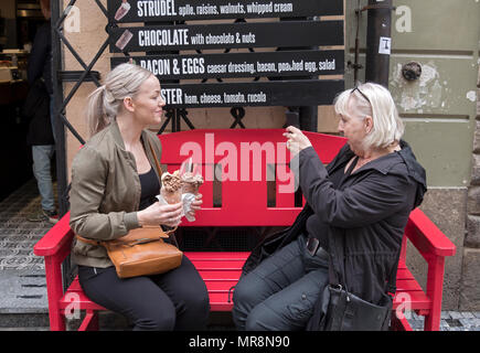 Eine Frau braucht ein Handy Foto einer jungen Dame mit der Trdelnik Eis Sie sind zu essen. In der Altstadt von Prag, tschechische Republik. Stockfoto