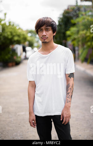 Jungen asiatischen Menschen mit Tätowierungen in den Straßen im Außenbereich Stockfoto