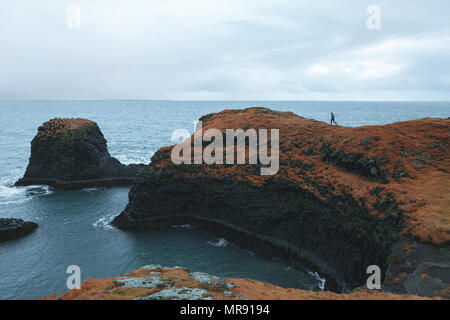 Mann auf einer Klippe am Meer, Arnarstapi, Island Stockfoto