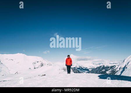 Junge Mann in die Kamera lächeln beim Stehen in der schneebedeckten Berge im Skigebiet Mayrhofen, Österreich Stockfoto