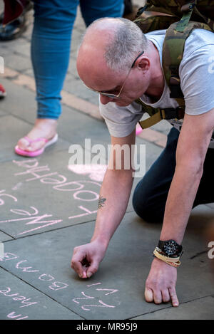 Leute schreiben Nachrichten, Blumen und Tribute in St. Ann's Platz, der vor dem Manchester zusammen Konzert im Gedenken an die Opfer der Arena Bombenattentat in Manchester, Großbritannien, am 22. Mai 2018. Prinz William und der britische Premierminister Theresa May zusammen mit anderen Politikern, sowie Angehörige der Getöteten, und Rettungskräfte zur Szene des Terror Angriff, während Tausende von Menschen in Manchester Dienstag versammelten sich am ersten Jahrestag des Terrorangriffs in der Stadt die 22 Toten. Stockfoto