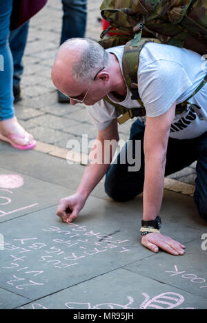 Leute schreiben Nachrichten, Blumen und Tribute in St. Ann's Platz, der vor dem Manchester zusammen Konzert im Gedenken an die Opfer der Arena Bombenattentat in Manchester, Großbritannien, am 22. Mai 2018. Prinz William und der britische Premierminister Theresa May zusammen mit anderen Politikern, sowie Angehörige der Getöteten, und Rettungskräfte zur Szene des Terror Angriff, während Tausende von Menschen in Manchester Dienstag versammelten sich am ersten Jahrestag des Terrorangriffs in der Stadt die 22 Toten. Stockfoto