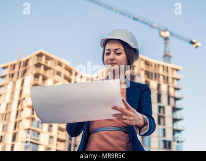 Wunderschöne Business woman Ingenieur steht mit plan Papiere. Stockfoto