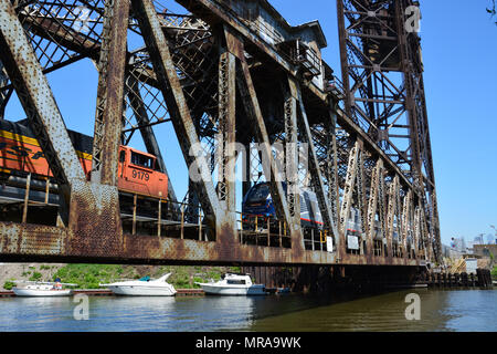 Eine Amtrack Personenzug und BNSF Güterzug über den Chicago River auf der Canal Street railroad Hubbrücke im Süden von Chicago. Stockfoto