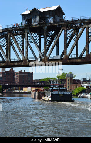 Die tugboat Kiowa schiebt ein leerer Lastkahn Süden unter der angehobenen Canal Street Eisenbahnbrücke am südlichen Zweig der Chicago River. Stockfoto