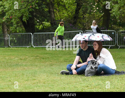 Swansea, South Wales, UK. 26. Mai 2018. Ein paar Schutz vor dem Regen unter einem Sonnenschirm während der Radio One Größte Wochenende Festival in Swansea Singleton Park. Das Radio eine Größte Wochenende hat sich das Festival Sommer Saison gekickt, die sah Tausende strömen in Swansea in Wales, UK zu sehen fungiert als Saugen, Ed Sheeran, gleichen Smith, George Esra und Craig David. Credit: Robert Melen/Alamy Leben Nachrichten. Stockfoto