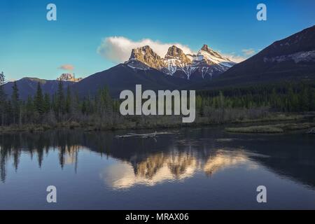 Die Three Sisters Mountain Peaks spiegeln sich im ruhigen Wasser des Sees wider. Landschaftlich Reizvolle Abendlandschaft Bow Valley Canmore Ausläufer Der Kanadischen Rocky Mountains In Alberta Stockfoto