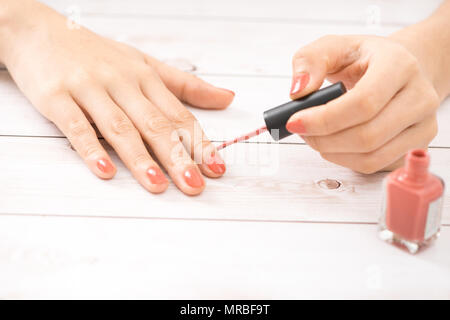 Weibliche Hände mit roten Maniküre und eine offene Flasche des Lacks auf dem Tisch Stockfoto