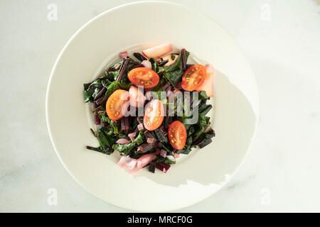 Frische gehackte Zuckerrüben, Tomaten und Zwiebeln gedünstet Salat serviert auf einem weißen Teller Stockfoto