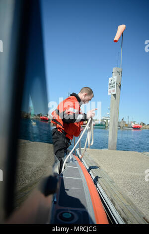 U.S. Coast Guard Petty Officer 3rd Class Ian Burgess sagt der Steuermann die Entfernung vom Boot zum Pier, Freitag, 14 April, 2017, in Sandwich, Massachusetts. Wie ein Boot crewmember, die Handhabung von Notfall- und Unfall- steuerung sind nur einige der Burgess' Verantwortlichkeiten. Stockfoto