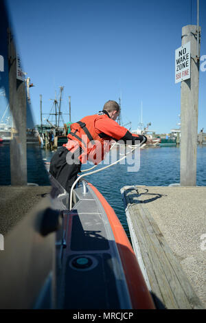 U.S. Coast Guard Petty Officer 3rd Class Ian Burgess wirft die Linie an die Steckvorrichtung an der Pier, Freitag, 17. April 2017, in Sandwich, Massachusetts. Wie ein Boot crewmember, die Handhabung von Notfall- und Unfall- steuerung sind nur einige der Burgess' Verantwortlichkeiten. Stockfoto