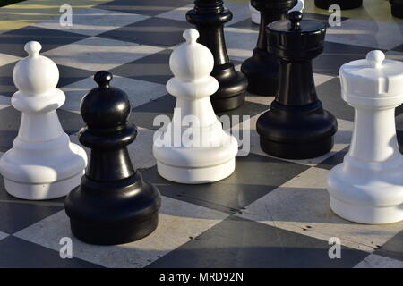 Giant outdoor Schachbrett mit einigen Stücken werfen lange Schatten am späten Abend licht. Stockfoto