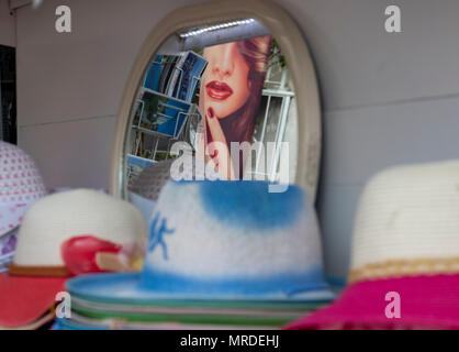 Womans Gesicht auf Werbung in einem Spiegel an einen Hut stall in Paphos Hafen Nordzypern wider. Stockfoto