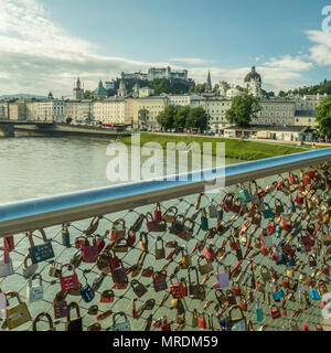 Liebe Vorhängeschlösser auf einer Brücke über die Salzach mit der mittelalterlichen Festung Hohensalzburg auf dem festungsberg im Hintergrund. Stockfoto