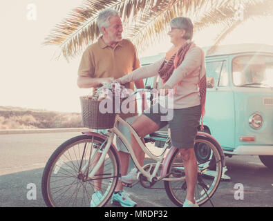 Mann und Frau kaukasischen reifen Spaß haben mit alten Fahrrad und Vintage van. Ferienhäuser und glücklich pensionierte Konzept. Hintergrundbeleuchtung von Sun für nette Modelle Stockfoto