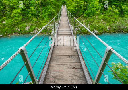 Das herrliche türkisblaue Wasser des Flusses Soca und die hölzerne Brücke. Wackelige Brücke bringt den Wanderer auf die andere Seite, in die Wälder Stockfoto