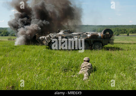 Der Soldat mit der Ukraine 1 Airmobile Bataillon, 79 Air Assault Brigade wartet hinter einem ukrainischen gepanzerten persönlichen Träger während der platoon Bewegung und Angriff bohrt mit der yavoriv Combat Training Center. Yavoriv CTC Personal, zusammen mit Mentoren aus 45Th der US Army Infantry Brigade Combat Team, führte die Ausbildung von Soldaten aus dem 1-79 Th während der Drehung des Bataillon durch die YAVORIV CTC. Der 45. ist in der Ukraine als Teil des Gemeinsamen multinationalen Ausbildung Group-Ukraine, eine internationale Koalition für eine Verbesserung der Ausbildung der Fähigkeit des CTC und Gebäude Professional bereitgestellt Stockfoto