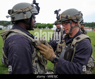 Spc. Ross Talpey, von Bridgewater, Massachusetts (rechts) führt vor der Bekämpfung der Kontrollen der anderen Squad Mitglied Pfc. Franklin Perry von Boston vor einer Nacht Mission während der jährlichen Ausbildung an der Joint Multinational Readiness Training Center in Hohenfels, Deutschland Juni 5, 2017. Die beiden Gardisten, zusammen mit Kolleginnen und Kollegen der Bravo Company, 1-182 nd Infanterie Regiment, Massachusetts Army National Guard dienen als die gegnerische Streitmacht, die in der übung kombinierte Lösen VIII, die rund 3.400 Mitarbeiter aus 10 Ländern. Das Ziel der Übung ist es, die Kräfte in Europa vorbereiten, zusammen zu t betreiben Stockfoto