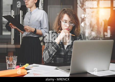 Weibliche Architekt oder Designer mit Brille hält Bleistift in der Hand und arbeiten mit modernen Laptop im Dachboden. Business woman Arbeiten mit Dokument Stockfoto