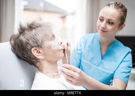 Care worker einfügen Nasal-sonde in der älteren Frau. Stockfoto