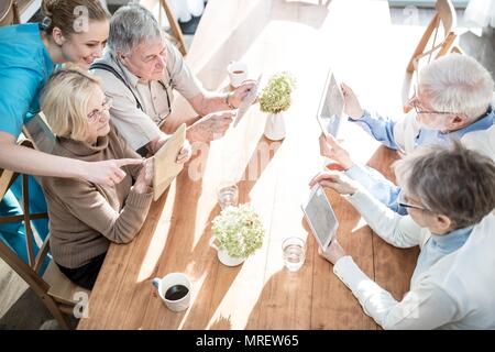 Ältere Erwachsene mit digitalen Tabletten in der Pflege zu Hause. Stockfoto