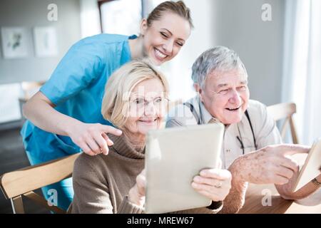 Senior Paar mit digitalen Tabletten in der Pflege zu Hause. Stockfoto