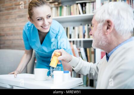 Care worker und älterer Mann mit Medizin Flasche. Stockfoto