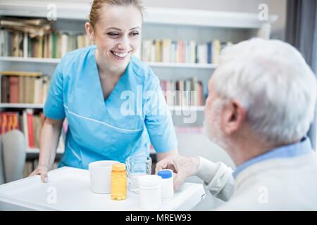 Care worker und älterer Mann mit Medizin Flaschen. Stockfoto