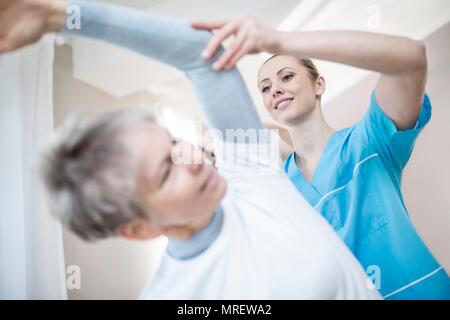 Ältere Frau, Stretching, Physiotherapeuten helfen. Stockfoto