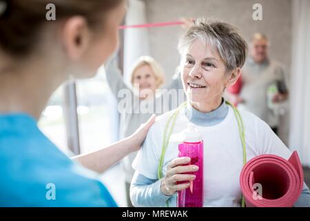 Ältere Frau im Gespräch mit Physiotherapeuten. Stockfoto