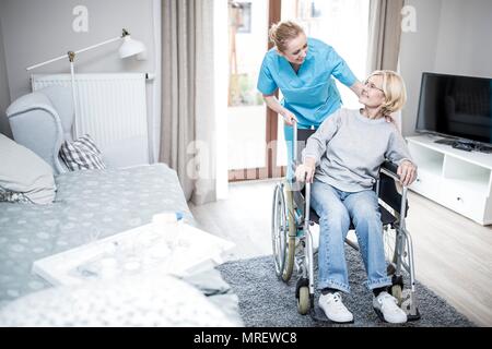 Ältere Frau im Rollstuhl mit care Worker in der Pflege zu Hause. Stockfoto