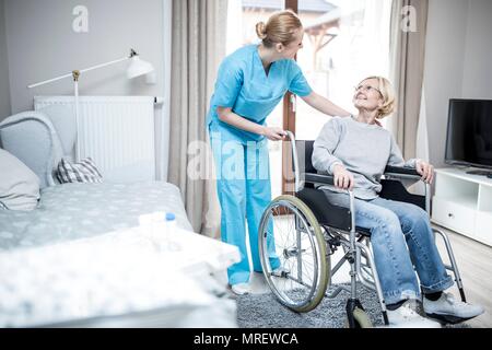 Ältere Frau im Rollstuhl mit care Worker in der Pflege zu Hause. Stockfoto