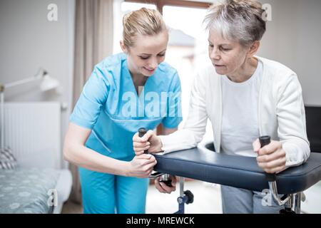 Ältere Frau mit rollator mit Sorgfalt Arbeitnehmer unterstützen. Stockfoto