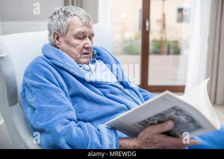 Älterer mann lesen Magazin in der Pflege zu Hause. Stockfoto
