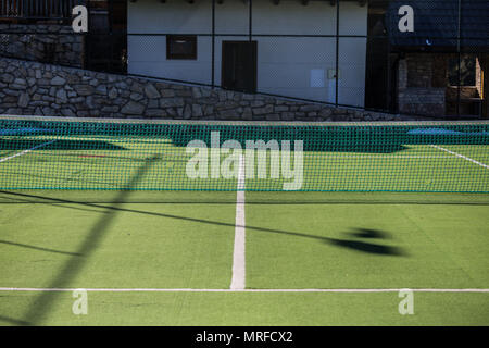 Eine leere Tennisplatz, mit begrasten Fläche und ein schützendes Netz rund um das Gelände, eine skizzierte Linie spielen Stockfoto