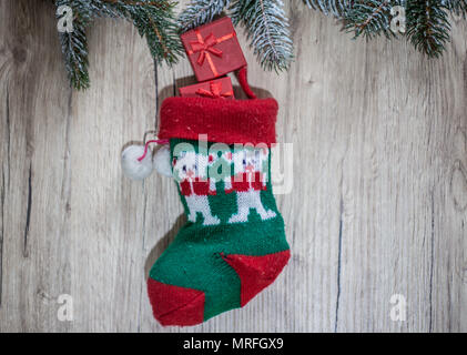Geschenk mit Weihnachten Band mit einer wollenen Rote Socke auf einer hölzernen Hintergrund Stockfoto