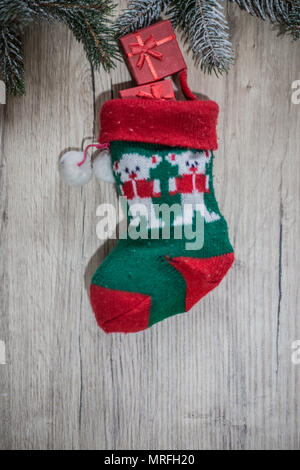 Geschenk mit Weihnachten Band mit einer wollenen Rote Socke auf einer hölzernen Hintergrund Stockfoto